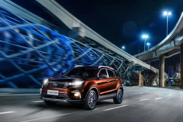 Um Ford Territory em movimento sob um viaduto iluminado em azul